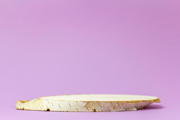 An empty podium made of cut wood on a delicate lilac background A layout for the presentation of a product cosmetics or perfumes