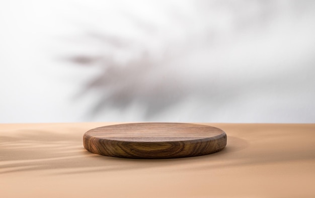 Empty podium with a shadow palm leaf A round wooden stage on a beige table