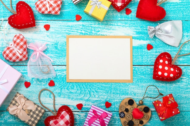 Empty post card with gift boxses and hearts on wooden table.