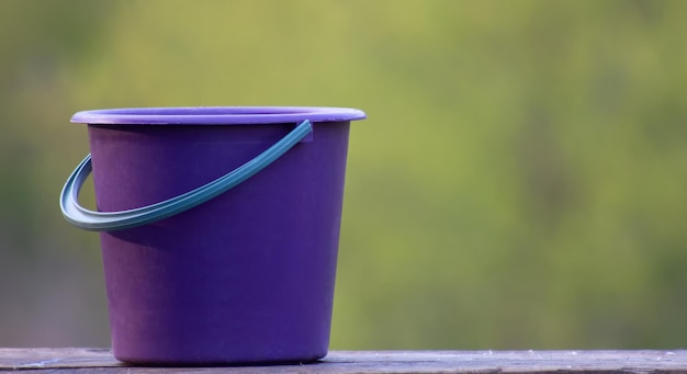 Secchio da giardino viola vuoto sul primo piano di tavole di legno