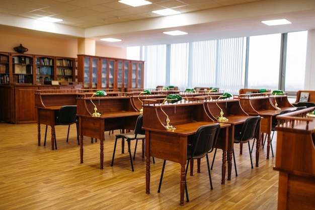 Foto sala di lettura vuota, file di tavoli in biblioteca, nessuno. deposito di conoscenza, scaffale con libri, concetto di educazione