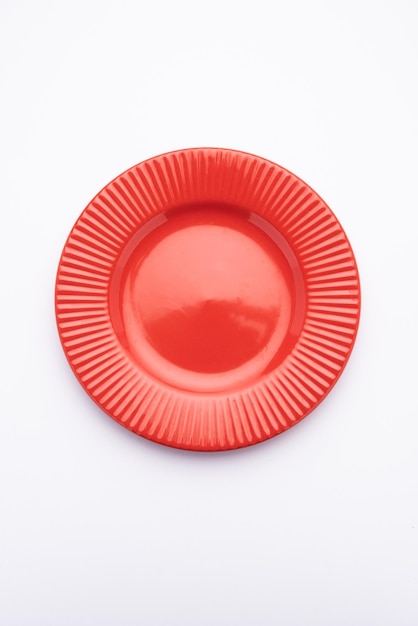 Piatto in ceramica rosso vuoto isolato su sfondo bianco