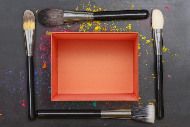 Empty red gift box with makeup brushes on black background