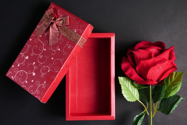 Empty red gift box with red rose on black background. Concept of Valentine Day.