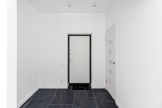 Empty renovated room in light colors with a black door The front door to the house