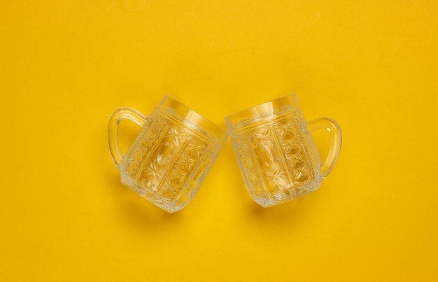 Empty retro faceted beer glasses on a yellow background. Top view