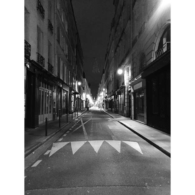 Empty road along buildings at night