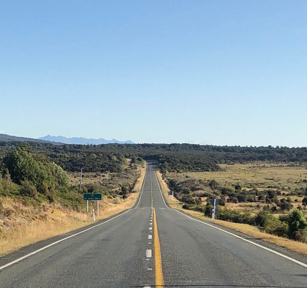 Empty road along landscape against clear sky