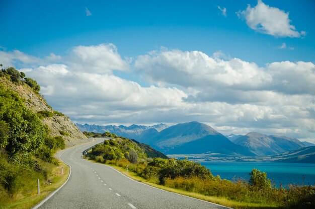 Empty road along landscape and mountains against sky