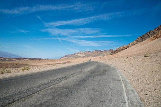 Empty road amidst desert against sky