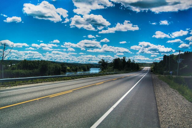 Photo empty road amidst field against cloudy sky