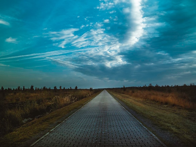 Foto strada vuota in mezzo al campo contro il cielo