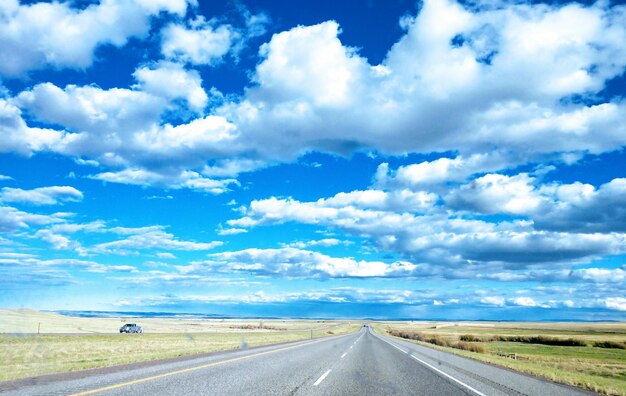 Foto strada vuota in mezzo al campo contro il cielo