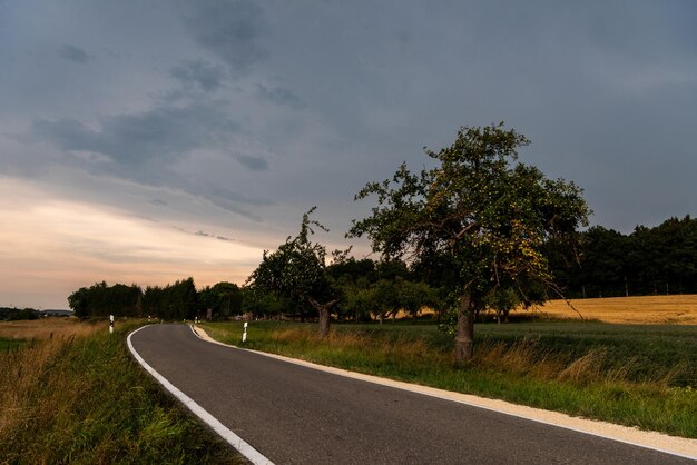 Empty road amidst field against sky