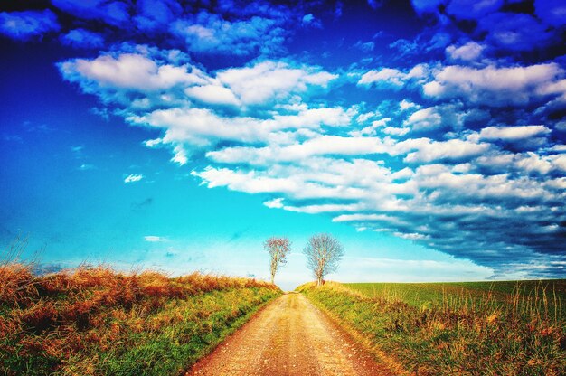 Foto strada vuota in mezzo a un paesaggio erboso contro un cielo nuvoloso