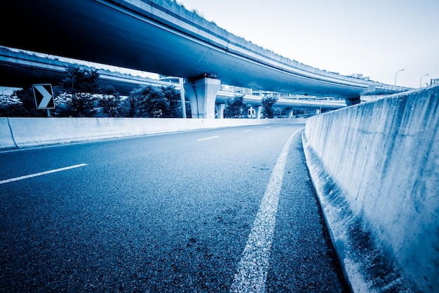 Empty road by bridge against sky in city