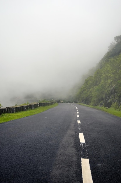 空の道と森と山の中の濃い雲傾斜した道路の経路上の暗い雲