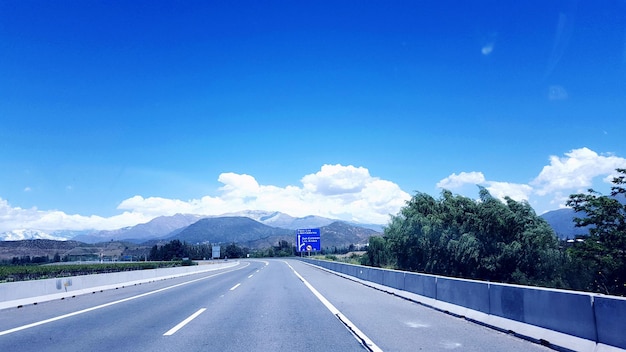 Empty road leading towards mountains against sky