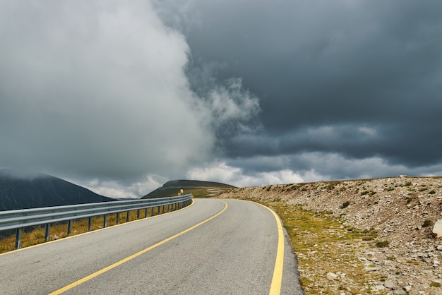 Empty road in mountains with dramatic sky