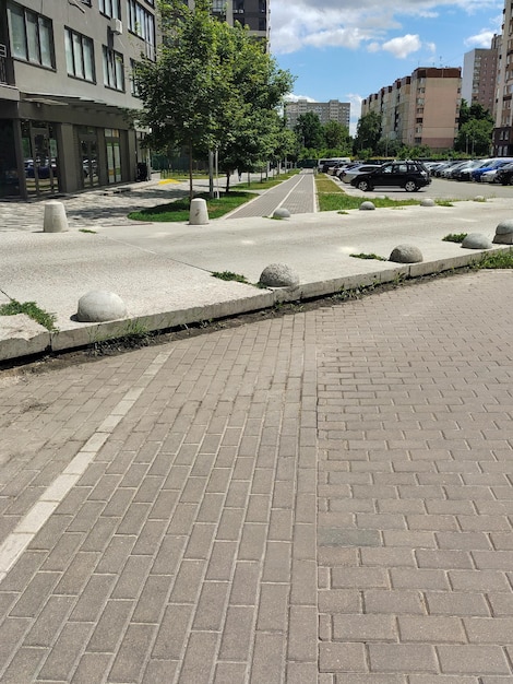 Empty road and pedestrian sidewalk in a modern city with a parking lot with cars in the distance