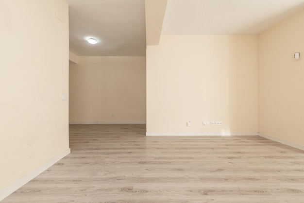 Empty room of an apartment with white wooden doors and skirting boards a light wooden floor and cream painted walls