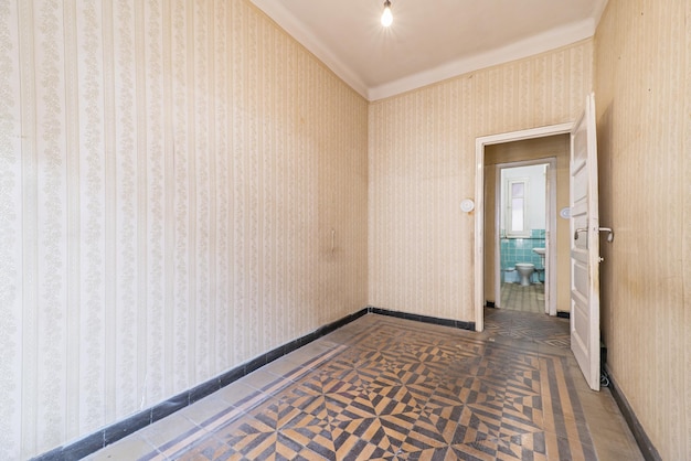 Empty room in an old house that looks like a time capsule with hydraulic tiled floors and wallpapered walls