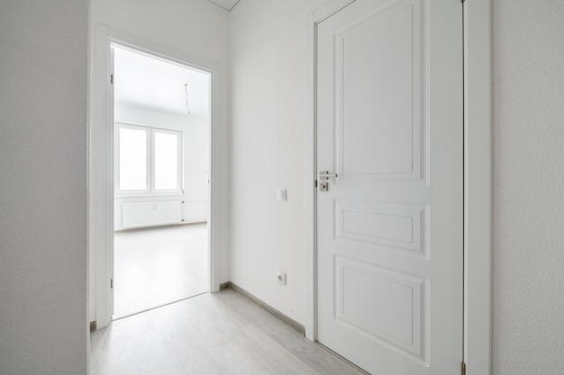 Empty room with laminate flooring and newly painted white wall in backgroundxA