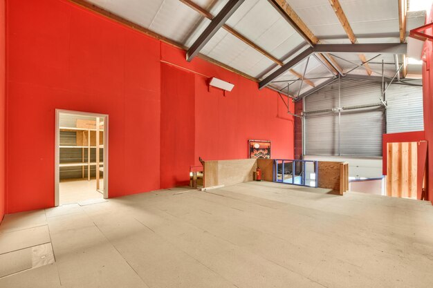 An empty room with red walls and wood beams on the ceiling as seen from the doorway to the left