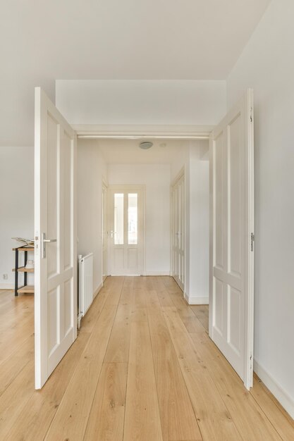 An empty room with white doors and a wood floor