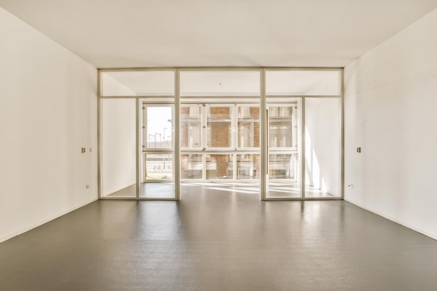 Photo an empty room with white walls and large glass doors that open to the outside looking out onto the street