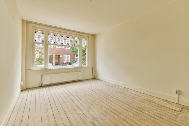 Photo an empty room with white walls and wood flooring in front of a large window looking out onto the street