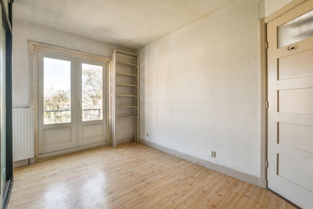 An empty room with wood flooring and white walls there is a door in the corner to the right