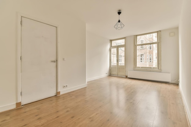 Una stanza vuota con pavimenti in legno e pareti bianche c'è una porta che porta al lato sinistro della stanza
