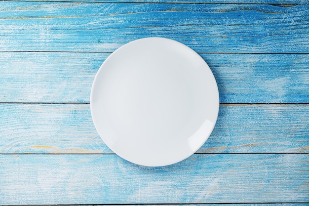 Empty round bowl on a blue wooden background from above. Free space