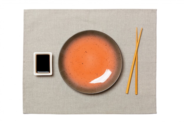 Photo empty round brown plate with chopsticks for sushi on grey napkin background