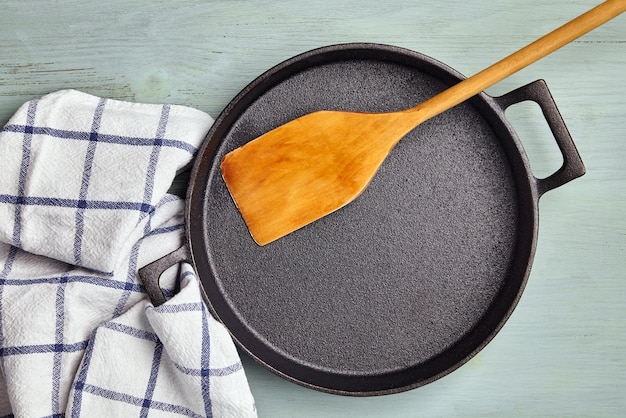 Photo empty round cast iron pan wooden spatula and tea towel napkin