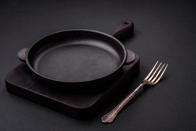 Empty round cast iron skillet on dark textured concrete background