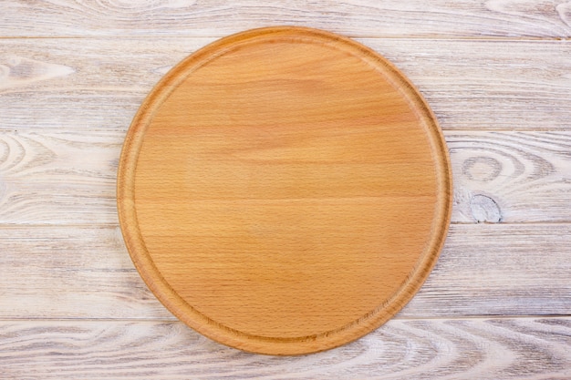 Empty round cutting board on a wooden table