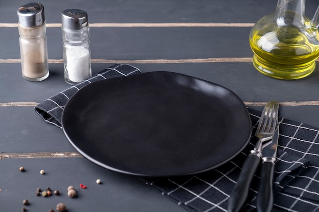 Empty round dark plate served with fork and knife.