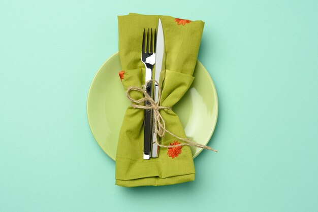 Empty round green ceramic plate and metal fork and knife