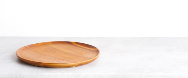 Empty round wooden plate on white cement table and brown cement wall background