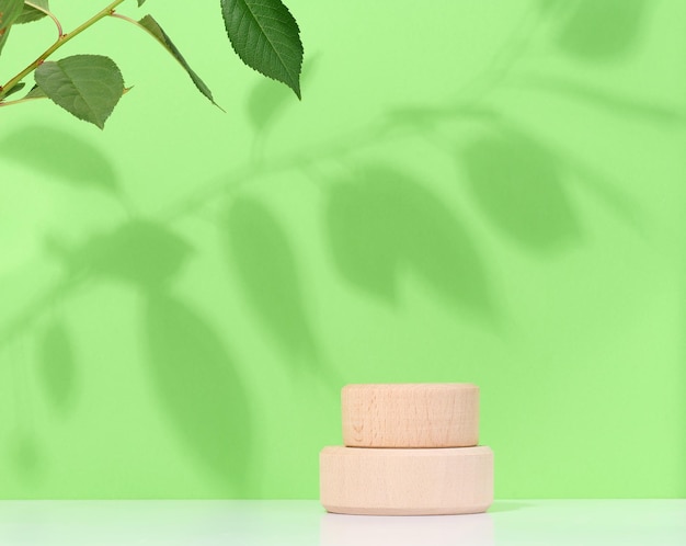 Empty round wooden platform on a green background Place for demonstration of products cosmetics