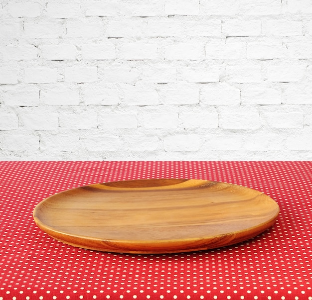赤い水玉のテーブルクロスで空の丸い木製トレイ