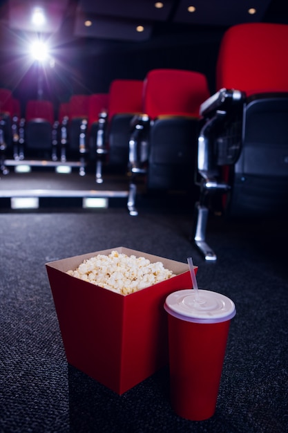 Empty rows of red seats with pop corn and drink on the floor