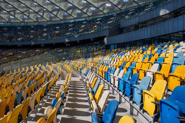 Empty rows of seats in a football olympic stadium with yellow and blue benches