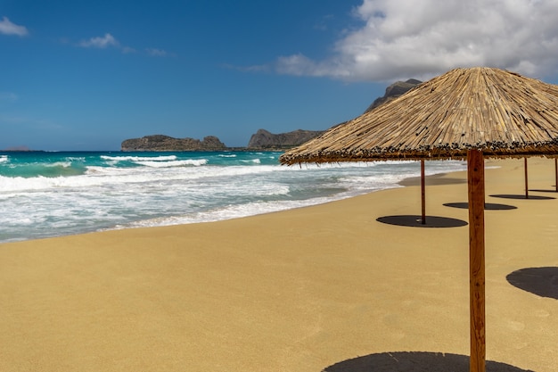 Пустой песчаный пляж с зонтиками летом при солнечном свете.