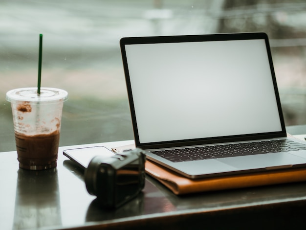 Empty screen laptop with camera and ice coffee in the cafe.