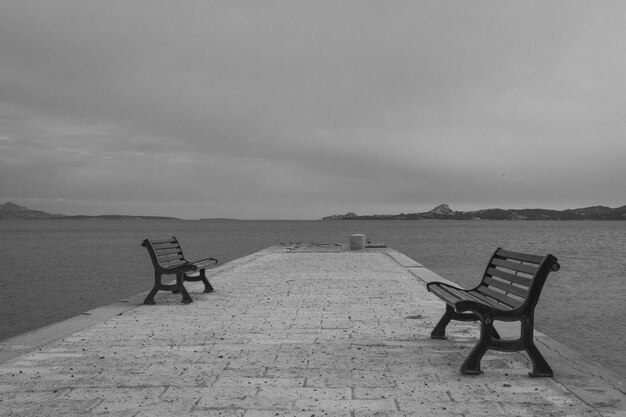 Empty seats on beach against sky