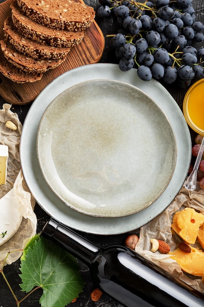 Photo empty serving plate in center frame made of honey grapes cheese snack other food ingredients gastronomy appetizer snacks. mock up copy space or template on blue plate dish top vertical.