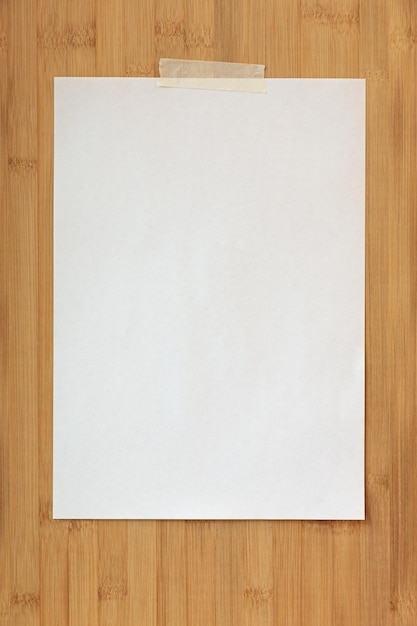 An empty sheet of paper is hanging on a wooden board